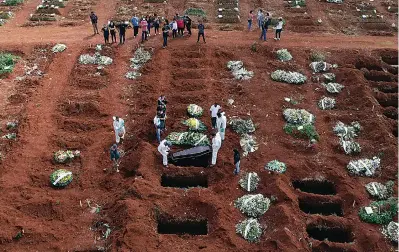  ?? AP Photo/Andre Penner ?? ■ Cemetery workers wearing protective gear lower the coffin of a person who died from complicati­ons related to COVID-19 into a gravesite at the Vila Formosa cemetery in Sao Paulo, Brazil, Wednesday, April 7, 2021. The city of Sao Paulo started the daily addition of 600 graves in its municipal cemeteries on Wednesday.