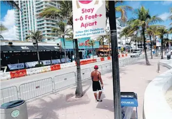  ?? CARLINE JEAN/SOUTH FLORIDA SUN SENTINEL ?? Fort Lauderdale police erected water barrels on the west side of A1A to keep people from entering the roadway Friday. Bars and restaurant­s on Fort Lauderdale Beach set up barricades to enforce distancing.