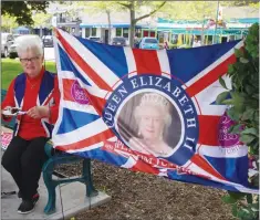  ?? ?? Phyllis Papineau enjoys a slice of Platinum Jubilee cake on a bench beside one of the Platinum Jubilee flags at Heritage Park.