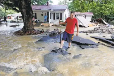  ?? STEVE HELBER/ASSOCIATED PRESS PHOTOS ?? Mark Bowes, of White Sulphur Springs, West Virginia, cleans up from severe flooding Friday. A deluge of 9 inches of rain destroyed or damaged more than 100 homes and knocked out power to tens of thousands of residences and businesses.
