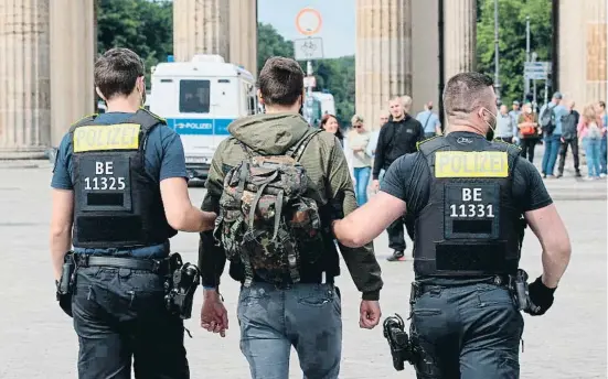  ??  ?? Un detenido, ayer frente a la puerta de Brandembur­go, en Berlín