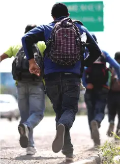  ?? — Reuters photo ?? Men belonging to a caravan of migrants from El Salvador en route to the United States, run after noticing the presence of police.