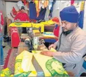  ??  ?? A tailor stitching farmer union flags and his co-worker printing the insignia in Amritsar on Sunday .
SAMEER SEHGAL/HT