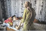  ??  ?? Aziz, 13, who is recovering from burns after setting himself on fire, with his mother Olfa at home in Bou Hajla.