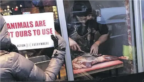  ?? MARNI JILL UGAR ?? Chef and owner Michael Hunter apparently brought the leg of a deer to the window of his Toronto restaurant last week and butchered it as animal rights protesters outside watched, clutching their signs that read “Murder.”