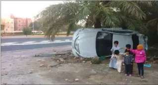  ??  ?? أطفال بجانب السيارة المنحرفة بعد الحادث ويبدو المنعطف الخطير المواجه لمنزل العجمي