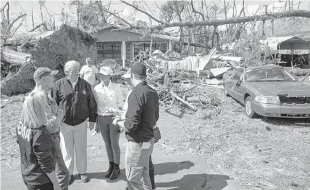  ?? EVAN VUCCI/AP PHOTOS ?? President Donald Trump talks with, from left: Homeland Security Secretary Kirstjen Nielsen, Florida Gov. Rick Scott, first lady Melania Trump, Margo Anderson, mayor of Lynn Haven, and FEMA Director Brock Long as they tour a neighborho­od affected by Hurricane Michael.