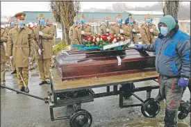  ?? (AP/Vadim Ghirda) ?? The coffin of Iancu Tucarman is transporte­d on a cart past an honor guard at a Jewish cemetery in Bucharest, Romania, on Jan. 11. Tucarman, one of the last remaining Holocaust survivors in Romania, was buried after dying from covid-19 at age 98.