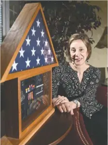  ?? STAFF PHOTO BY TIM BARBER ?? Dr. Maria Rabbio is shown with a boxed U.S. flag and other memorabili­a from her years as a military dentist.