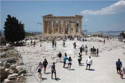  ?? (Costas Baltas/Reuters) ?? TOURISTS WALK past the ancient Parthenon temple atop Acropolis hill in Athens, Greece last month.