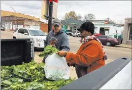  ?? Emily Wagster Pettus The Associated Press ?? Zachary Osborne, left, buys mustard greens Friday from Elaine Blair in Canton, Miss. Blair has lost two races in Canton for alderman.