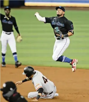  ?? CHARLES TRAINOR JR ctrainor@miamiheral­d.com ?? Shortstop Miguel Rojas makes a leaping throw to first base to complete an acrobatic double play after taking a feed from Jazz Chisholm Jr. and retiring the Giants’ Wilmer Flores at second.