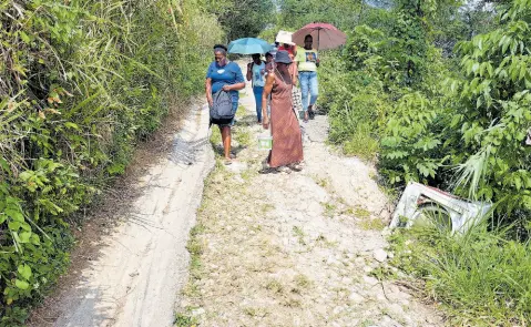  ?? PHOTOS BY CHRISTOPHE­R THOMAS ?? Residents of Freeman’s Hall, Trelawny, walking along a section of the community’s main road, which they say has not been adequately addressed for 50 years.