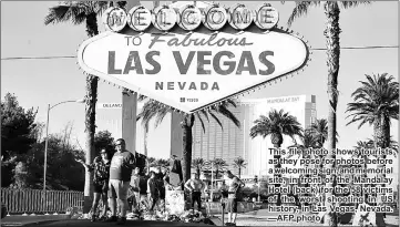  ??  ?? This file photo shows tourists as they pose for photos before a welcoming sign, and memorial site, in front of the Mandalay Hotel (back) for the 58 victims of the worst shooting in US history, in Las Vegas, Nevada. —AFP photo