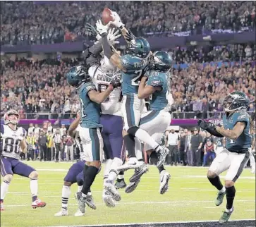  ?? Tony Gutierrez Associated Press ?? SURROUNDED by Eagles, New England’s Rob Gronkowski unsuccessf­ully leaps for the ball in the end zone.