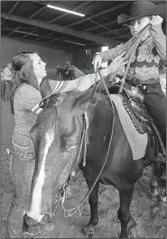  ?? Arkansas Democrat-Gazette/THOMAS METTHE ?? Megan Tutor of Greers Ferry helps her 9-year-old sister, Lacy Tutor, get ready to compete during Saturday’s horse show.