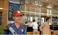  ?? — Bloomberg ?? A customer waits at a cash counter behind a security guard in a Bank Alfalah branch in Karachi. The bank’s net interest income for January- September 2013 was Rs12.519 billion, as compared to Rs13.879 billion in 2012.