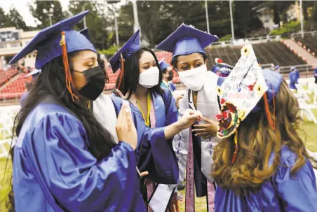  ?? Photos by Jessica Christian / The Chronicle ?? Above: Marvely Tomas (from left), Wendy Huang and Pierce Whitney admire Valeria Serrano’s cap at Balboa High’s graduation.