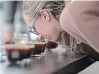  ??  ?? Shelby Merrithew inhales the aroma of a cup of hot coffee during a coffee cupping at Smile Tiger Coffee Roasters in Kitchener.