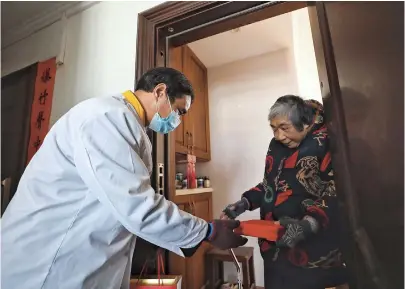  ??  ?? Zheng Shao, an elderly resident, receives a lunch box from Kong Weixiang. — Jiang Xiaowei