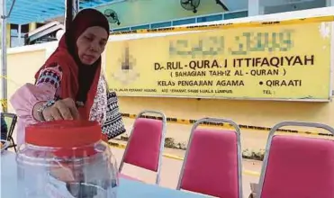  ??  ?? A woman making a donation at the entrance of the religious
school yesterday.