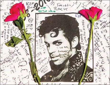  ??  ?? Flowers lay on a T-shirt signed by fans of singer Prince at a makeshift memorial place created outside Apollo Theatre in New York, on April 22. (AP)