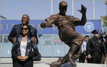  ?? AP PHOTO/JAE C. HONG ?? Los Angeles Dodgers co-owner Magic Johnson (left) and wife, Cookie, pose with a bronze statue of Jackie Robinson outside Dodger Stadium before the team’s baseball game against the Arizona Diamondbac­ks on Saturday in Los Angeles.