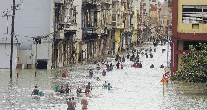  ?? RAMON ESPINOSA / THE ASSOCIATED PRESS ?? People move through flooded streets in Havana Sunday after hurricane Irma ripped through parts of Cuba. The powerful storm took roofs off houses, collapsed buildings and flooded hundreds of miles of coastline. Cuban officials warned residents to be...