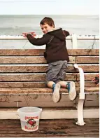  ??  ?? Armed with a line and bucket for his ‘catch’, a young visitor enjoys the simple pastime of crabbing from the edge of the pier.