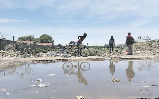  ?? Picture: Nigel Sibanda ?? Residents pass next to sewage water in Sharpevill­e, southern Gauteng, yesterday. The DA called for urgent interventi­on in failing municipali­ties to ensure that their financial crisis is turned around.