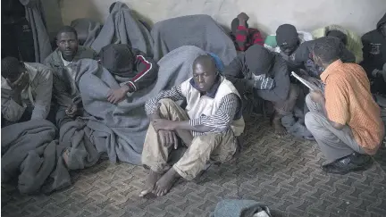  ?? THE ASSOCIATED PRESS FILES ?? African migrants cover themselves with blankets after being captured by the Libyan Coast Guard while on a boat heading to Italy. Smugglers offer transport to Libya and the chance of a boat trip to Europe, sometimes with no money down. But they later...