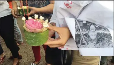  ?? MARTIN DE BOURMONT ?? A woman at a memorial service holds flowers and a photo of Pen Kunthea, a Phnom Penh sex worker who drowned while attempting to flee from district security guards.