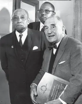  ?? THE COMMERCIAL APPEAL FILES ?? Jan. 1, 1968: Frank R. Ahlgren, editor of The Commercial Appeal, holds the “Man of the Year” award given him by the Beale Street Elks, as George W. Lee, left, general chairman of the Emancipati­on Day program, and the Rev. S.H. Herring, pastor of the host St. Paul Baptist Church, look on.