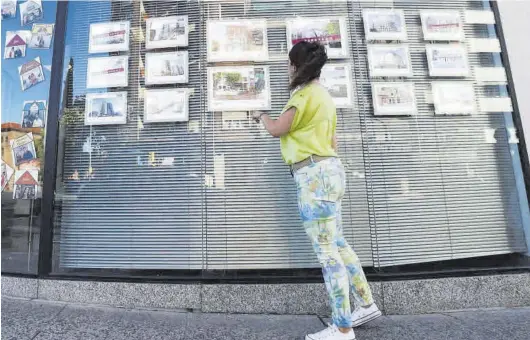  ?? ANDREEA VORNICU ?? Una joven observa las ofertas de vivienda colgadas en el escaparate de una agencia de Zaragoza.