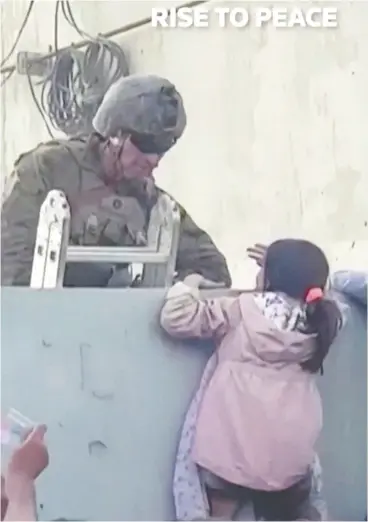 ?? COURTESY RISE TO PEACE / VIA REUTERS ?? A U.S. soldier stands guard earlier this week while a girl tries to climb the wall
as crowds gather at Kabul airport.