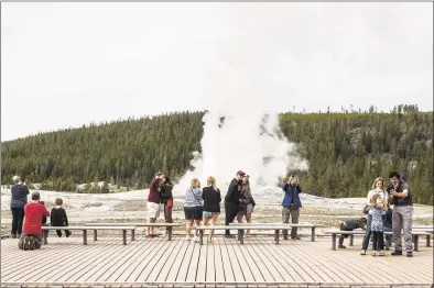  ?? Ryan Dorgan / Associated Press ?? Visitors watch as Old Faithful erupts on May 18, the day the park partially reopened after a two-month shutdown due to the coronaviru­s pandemic, at Yellowston­e National Park, Wyo. Officials at Yellowston­e and other national parks plan to let tourists mostly police themselves and not intervene much to enforce social distancing.