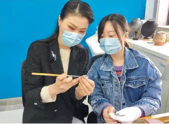  ??  ?? Huang Wen (left) guides a design trainee in jewelry- making. — Yang Jian