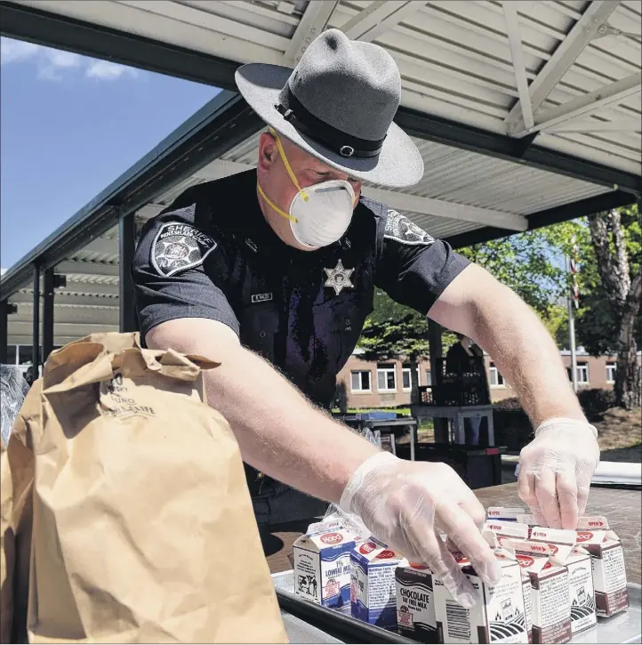  ?? Photos by Will Waldron / Times Union ?? Rensselaer County sheriff’s deputy Brian Nikles helps distribute meals at Averill Park High School. Nikles has been a major part of the school’s food distributi­on program since its first day of closure, serving food to all Averill Park students in need.