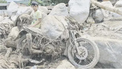  ?? Picture: AFP ?? BLEAK. A child sits next to a motorcycle destroyed by the mudslides in Mocoa, southern Colombia. The death toll from a devastatin­g landslide stood at about 250 yesterday.