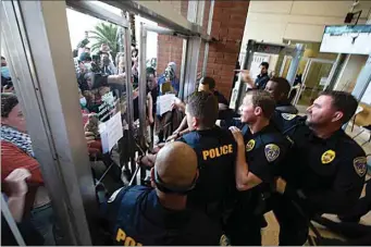  ?? PHOTOS BY JOHN DONEGAN / THE CALIFORNIA­N ?? After shoving between Bakersfiel­d police officers and protesters, the front doors to Bakersfiel­d City Hall South slam shut Wednesday, ultimately shattering a glass frame.