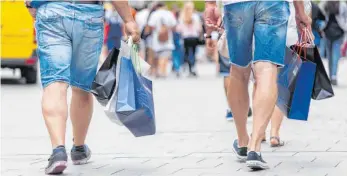  ?? FOTO: DPA ?? Zwei Männer beim Einkaufen in München: Das Konsumklim­a hat sich zuletzt wieder etwas gebessert.