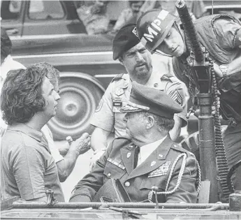  ?? | NEAL ULEVICH/ AP ?? Director Michael Cimino ( left) talks with Robert De Niro ( center, in beret) during a break in filming of “The Deer Hunter” in Bangkok, Thailand, Sept. 11, 1977.