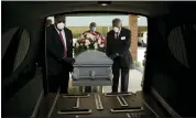  ?? THE ASSOCIATED PRESS FILE PHOTO ?? Mortician Cordarial O. Holloway, foreground left, and funeral director Robert L. Albritten, foreground right, place a casket into a hearse in Dawson, Ga.