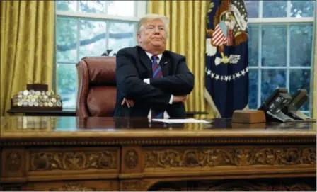  ?? EVAN VUCCI — THE ASSOCIATED PRESS ?? President Donald Trump crosses his arms after speaking with Mexican President Enrique Pena Nieto on the phone about a trade agreement between the United States and Mexico, in the Oval Office of the White House, Monday in Washington. Trump has bowed to widespread pressure from veterans groups and others to do more to honor John McCain’s death. Trump on Monday ordered flags at the White House and elsewhere lowered to half-staff until the six-term senator is buried Sunday. He also proclaimed “respect” for McCain, with whom he feuded bitterly for years. It was a marked reversal from Trump’s refusal to comment on McCain. Earlier Monday, the White House flag had been raised.