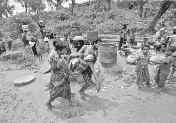  ??  ?? A Rohingya refugee is carried to safety after he collapsed while waiting to receive aid in Cox’s Bazar. — Reuters photo