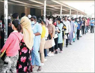  ?? ?? Long lines of expatriate workers standing outside in the sun waiting for their turn at a medical test centre.