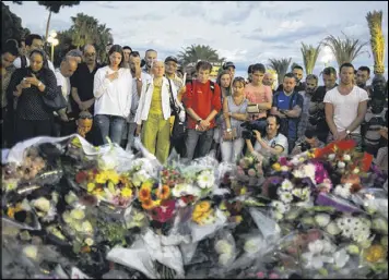  ?? DMITRY KOSTYUKOV / THE NEW YORK TIMES ?? People bring flowers to the site of a terrorist attack in Nice, France, on July 15. Some ordinary people in France have reacted heroically, risking their lives by fighting terrorists when they found themselves in the midst of an attack.