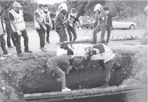  ??  ?? ANGGOTA bomba mengeluark­an mayat dari lubang pembetung parit di kawasan Batu 8, Jalan Bintulu-Miri.