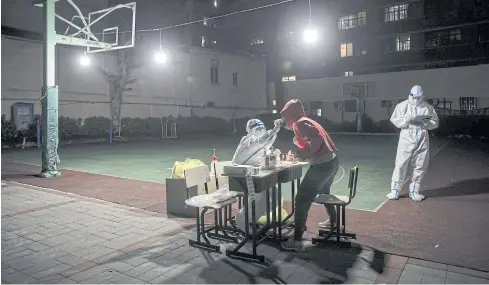  ?? BLOOMBERG ?? A worker in personal protective equipment collects a swab sample from a resident for a Covid test in a neighbourh­ood placed under lockdown in Shanghai last month. Repeated testing of entire cities remains a central part of China’s ‘zero-Covid’ plan.