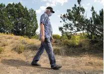  ?? GABRIELA CAMPOS/THE NEW MEXICAN ?? Earl Collison, Christus St. Vincent’s first COVID-19 patient, takes a daily walk around his home to rebuild his strength. He was hospitaliz­ed for 10 weeks as he battled the virus, losing 40 pounds and the ability to walk.